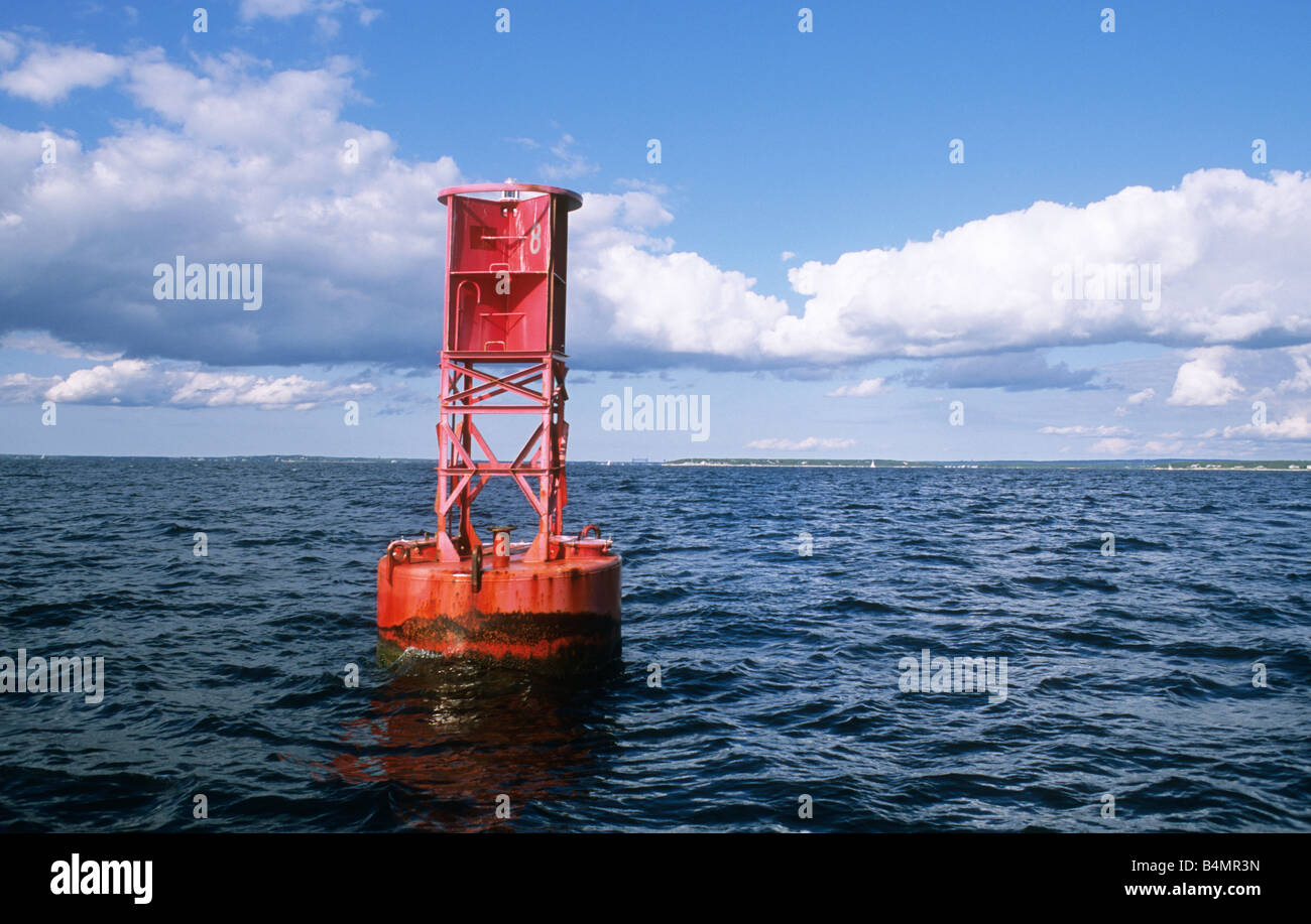 Red bell buoy in ocean channel marker with clouds and blue sky