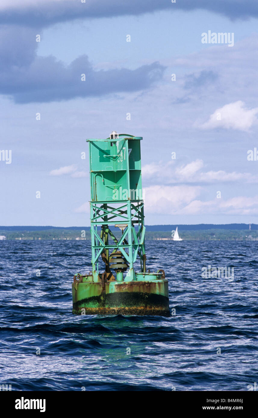 Green bell buoy channel marker in ocean with clouds and blue sky Stock