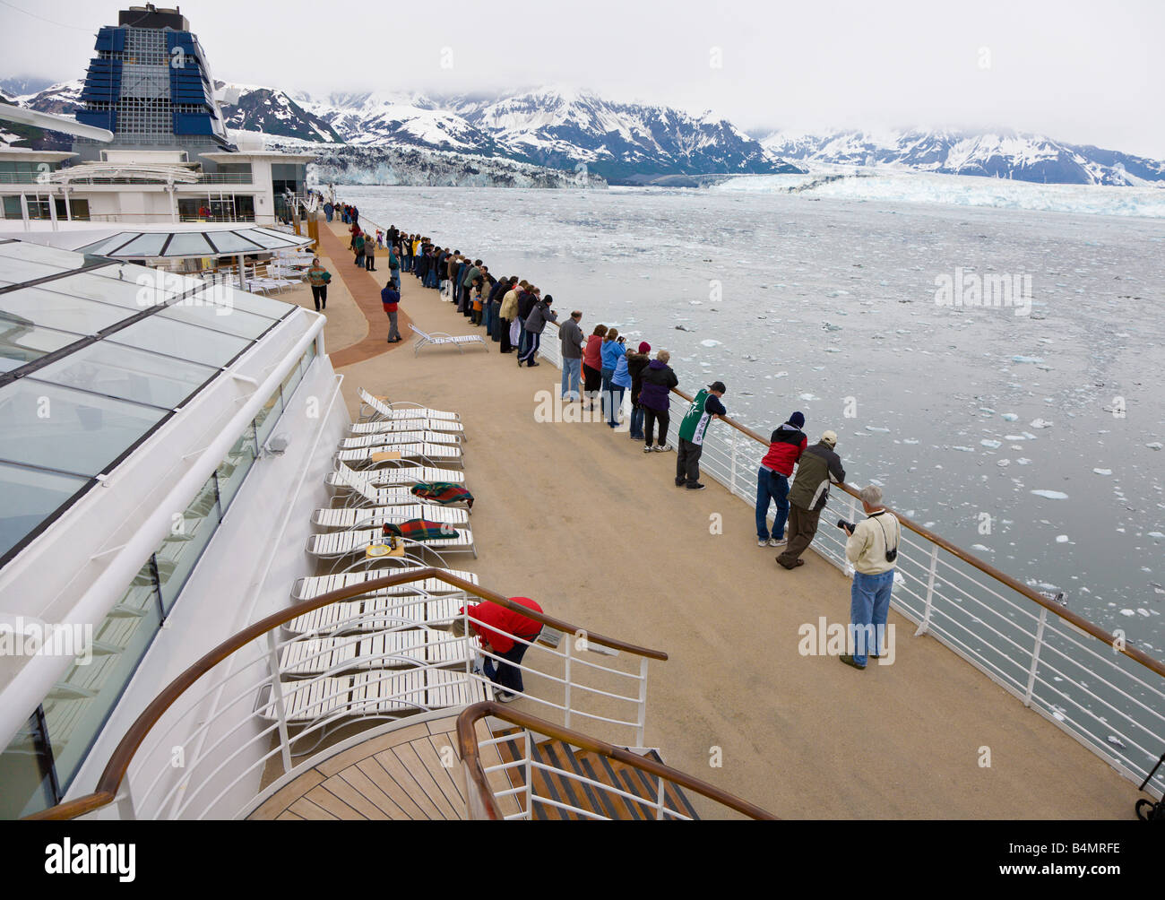 Cruise ship passengers line up along the ship rail to watch as the ship approaches Hubbard Glacier Stock Photo