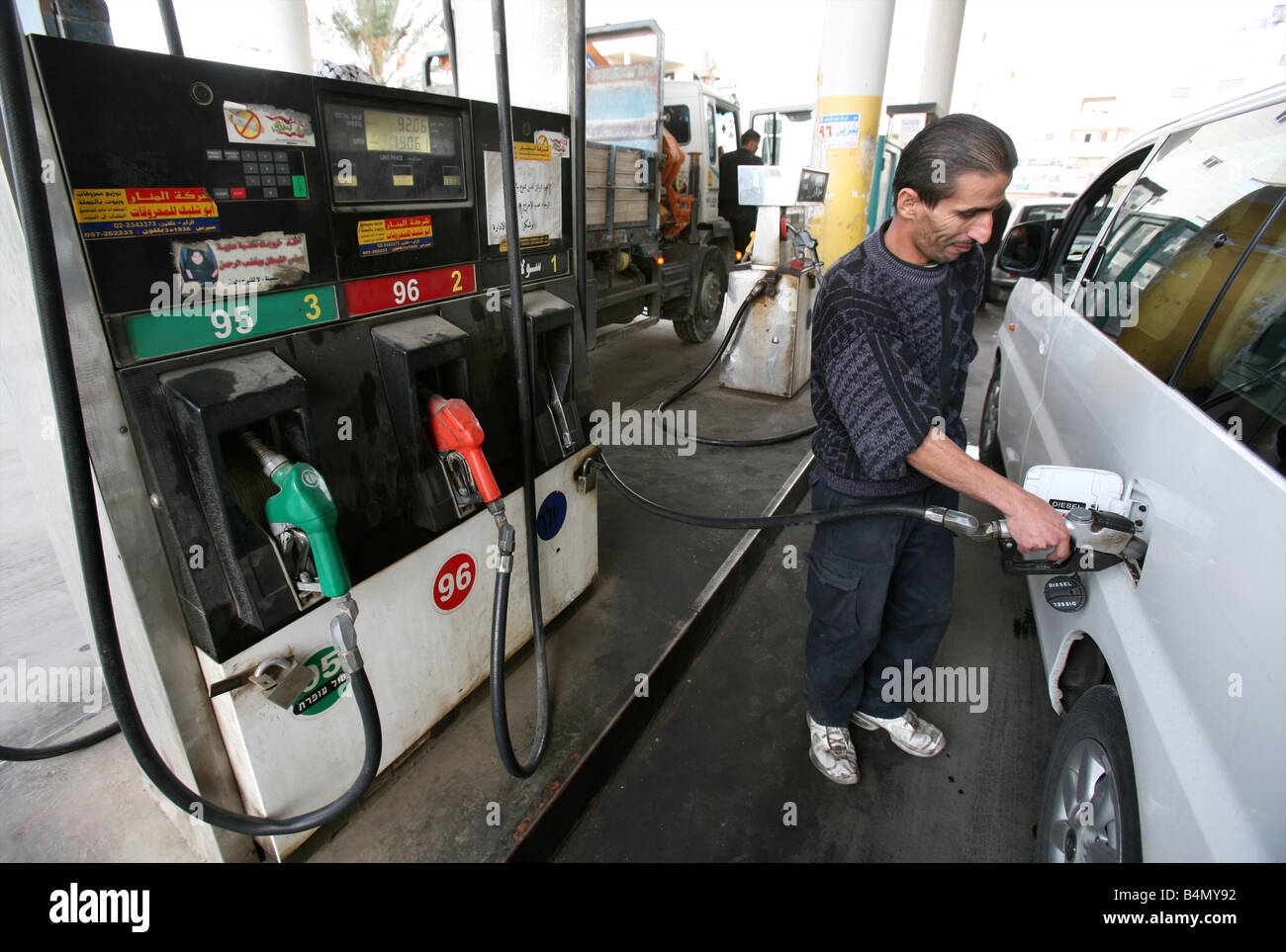 A man fills a car with gas near the wall Israel is around the west bank territories blocking access for Palestinians who feel imprisoned by it Stock Photo