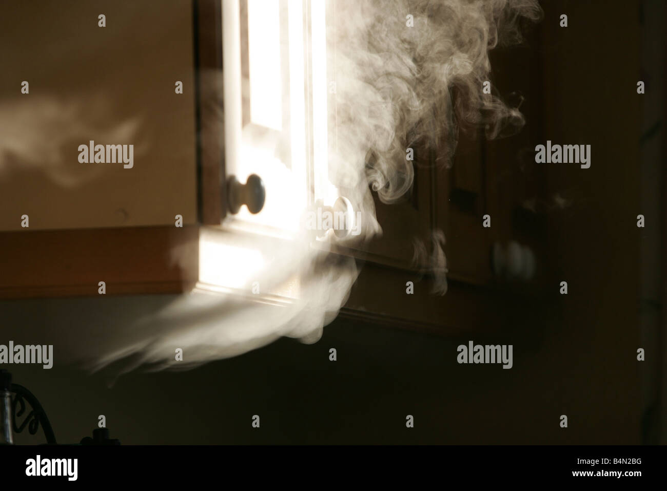 Smoke bellows out from under a cupboard Stock Photo