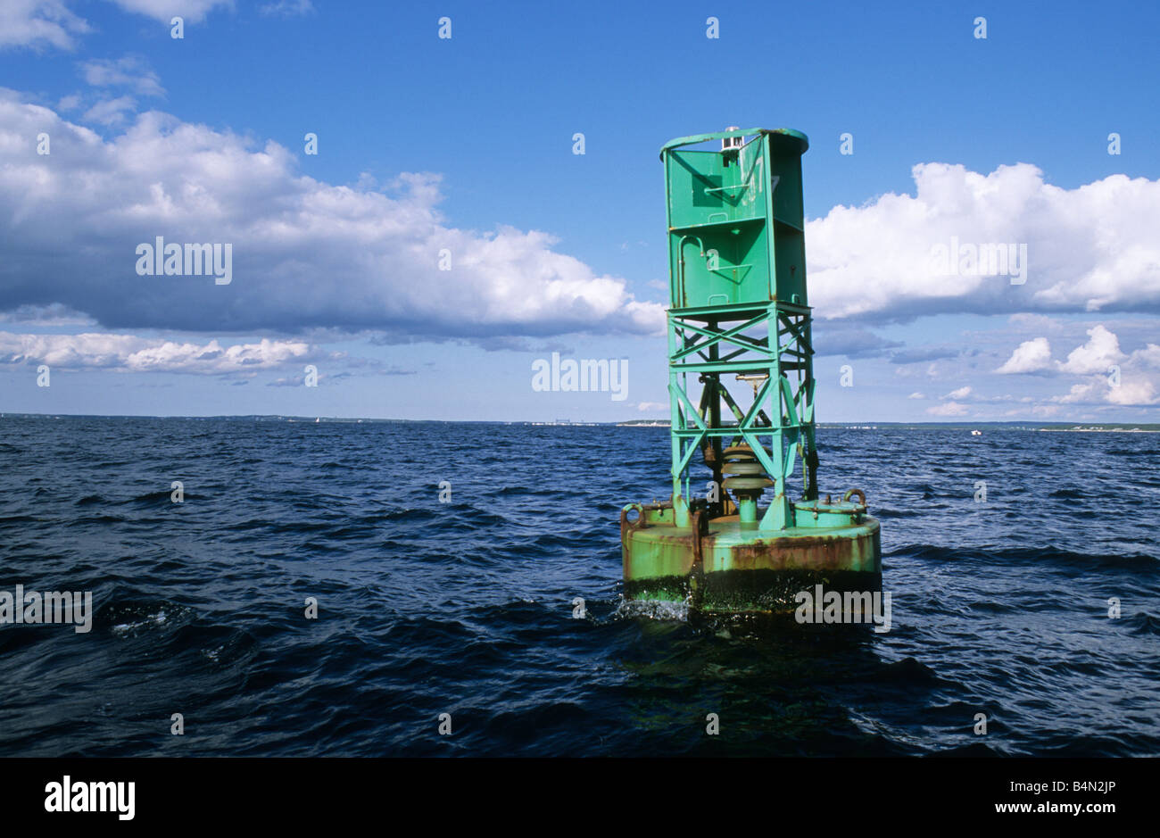 Green bell buoy in ocean channel marker with clouds and blue sky Stock