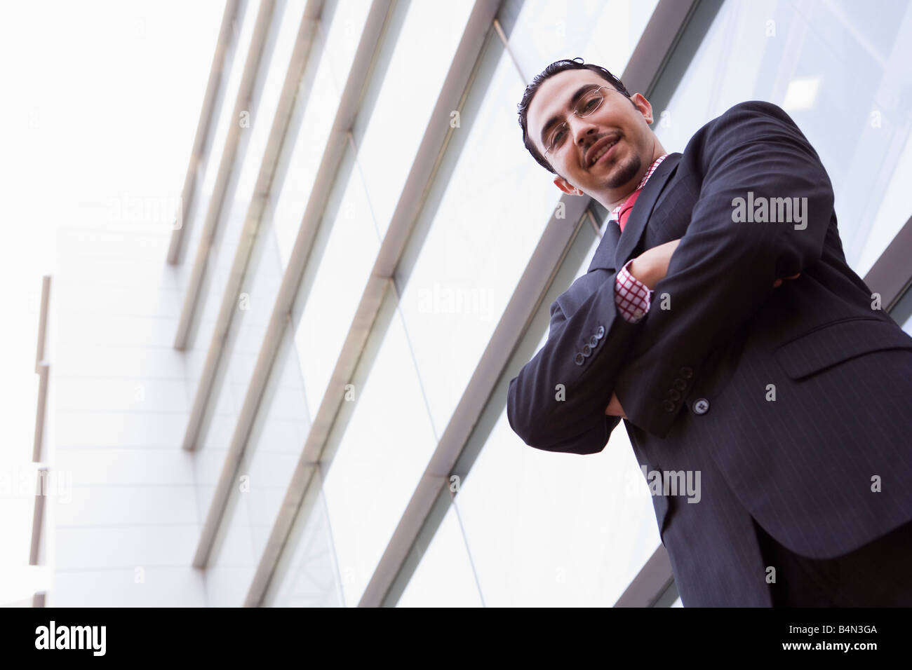 Businessman standing outdoors by building smiling (high key/selective focus) Stock Photo