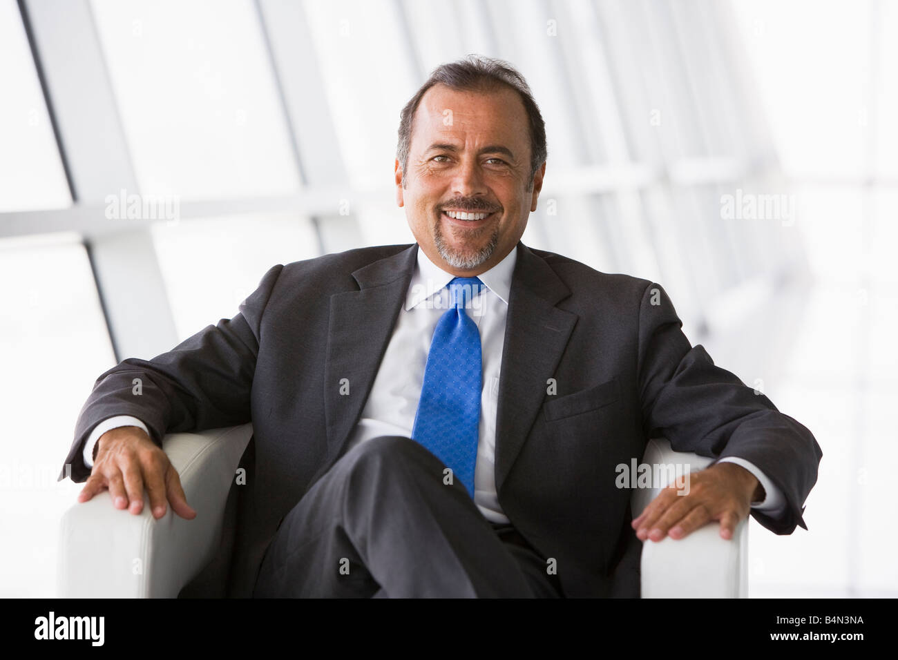 Businessman sitting indoors smiling (high key/selective focus) Stock Photo