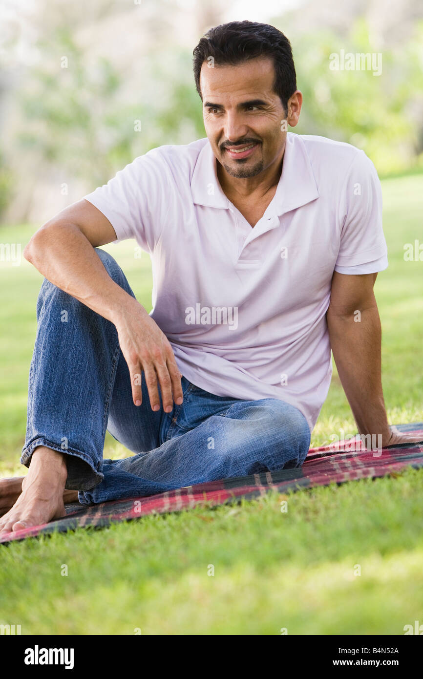 Man sitting outdoors at park smiling (selective focus) Stock Photo