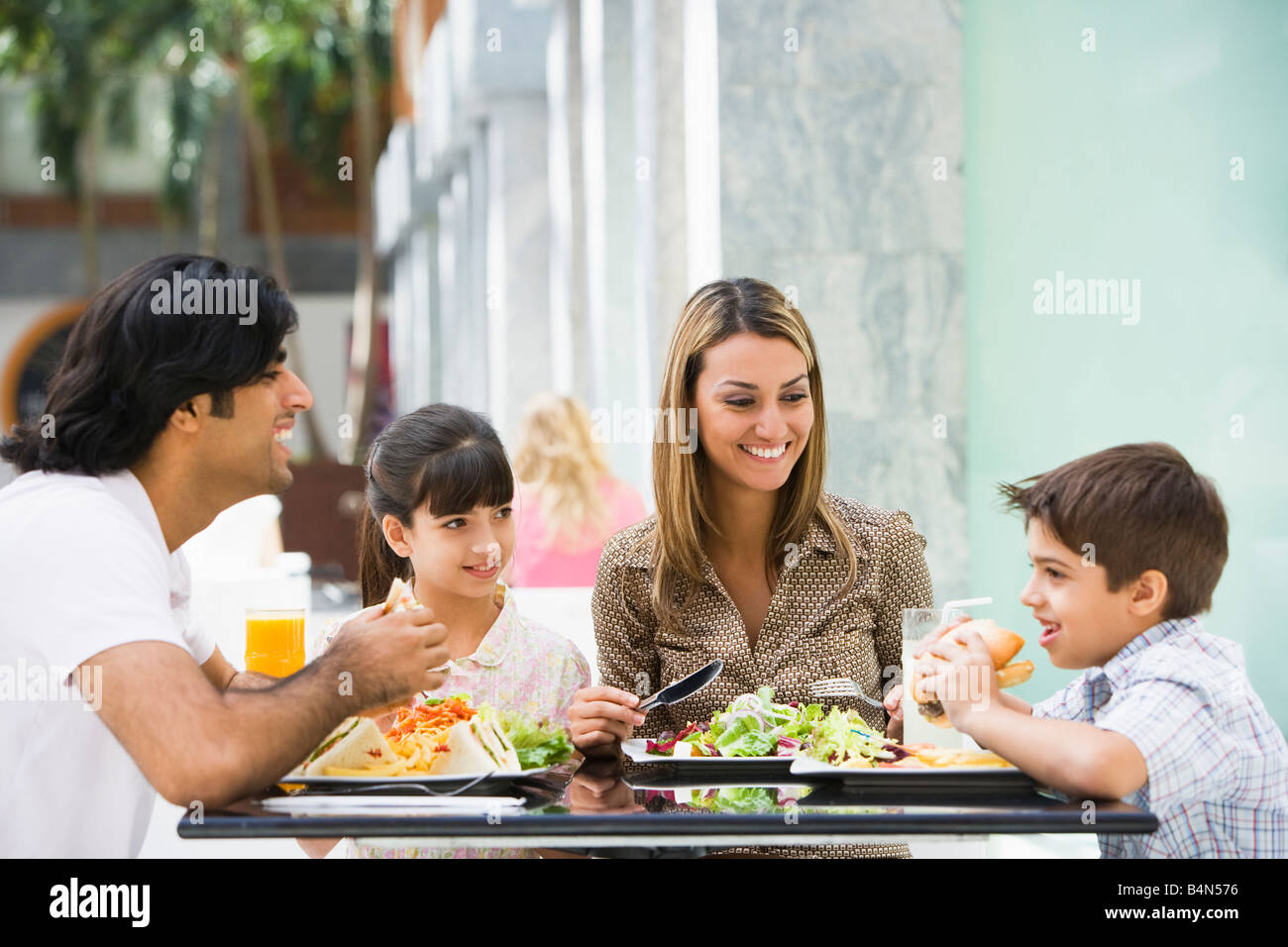Family at restaurant eating and smiling (selective focus) Stock Photo