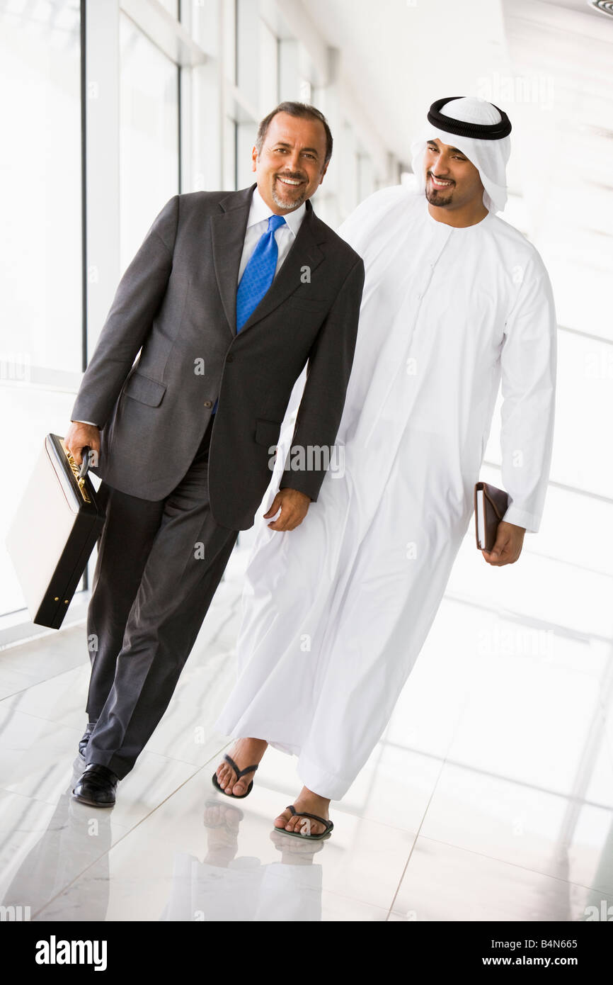Two businessmen walking in corridor smiling (high key/selective focus) Stock Photo