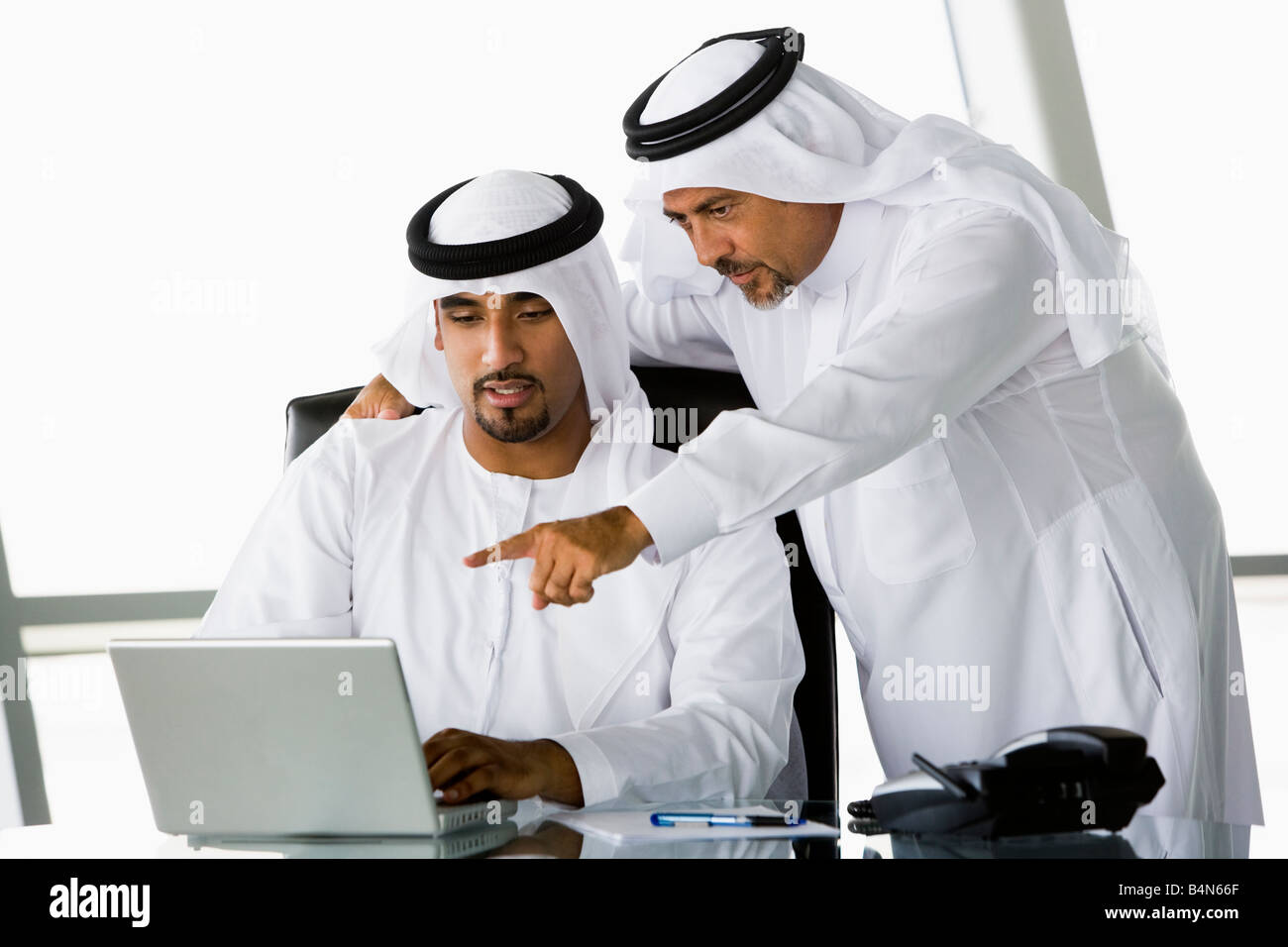 Two businessmen in office pointing at laptop (high key/selective focus) Stock Photo
