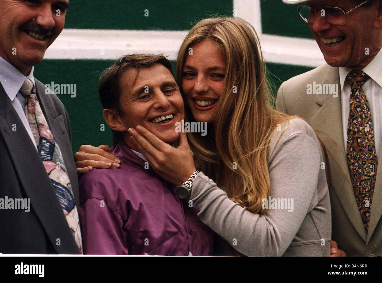 Willie Carwson Jockey wearing purple silks is hugged by Model Susan Mizzi as TV Presenter Bob Holness looks on Stock Photo
