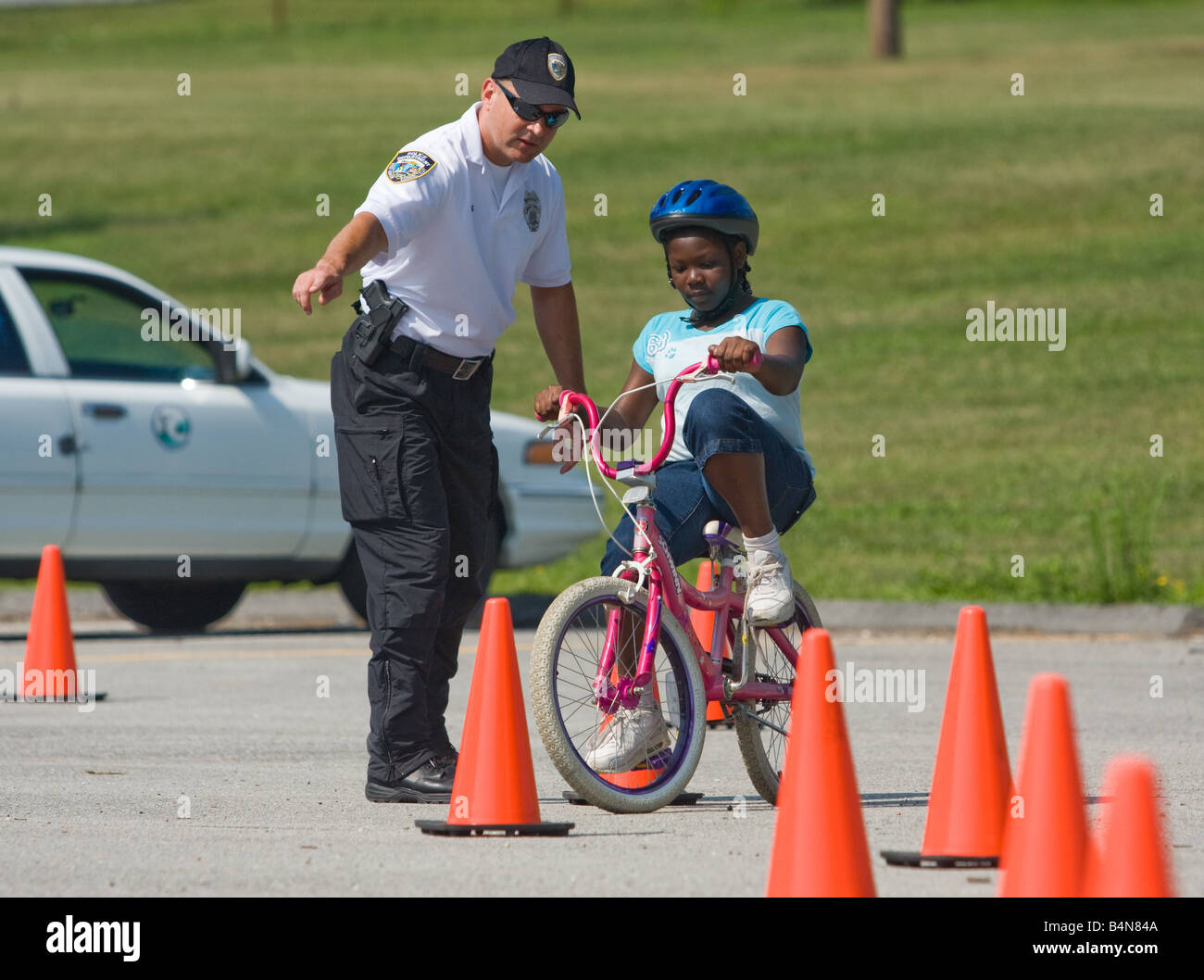 A Police Officer teaches a young cyclist how to ride safely during a summer camp safety program in Connecticut USA Stock Photo
