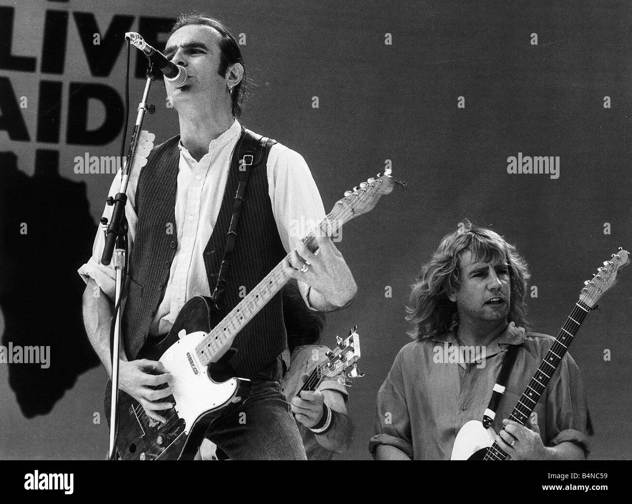 Francis Rossi lead singer with Pop Group Status Quo singing on stage at Live Aid concert Local Caption retromusic Stock Photo