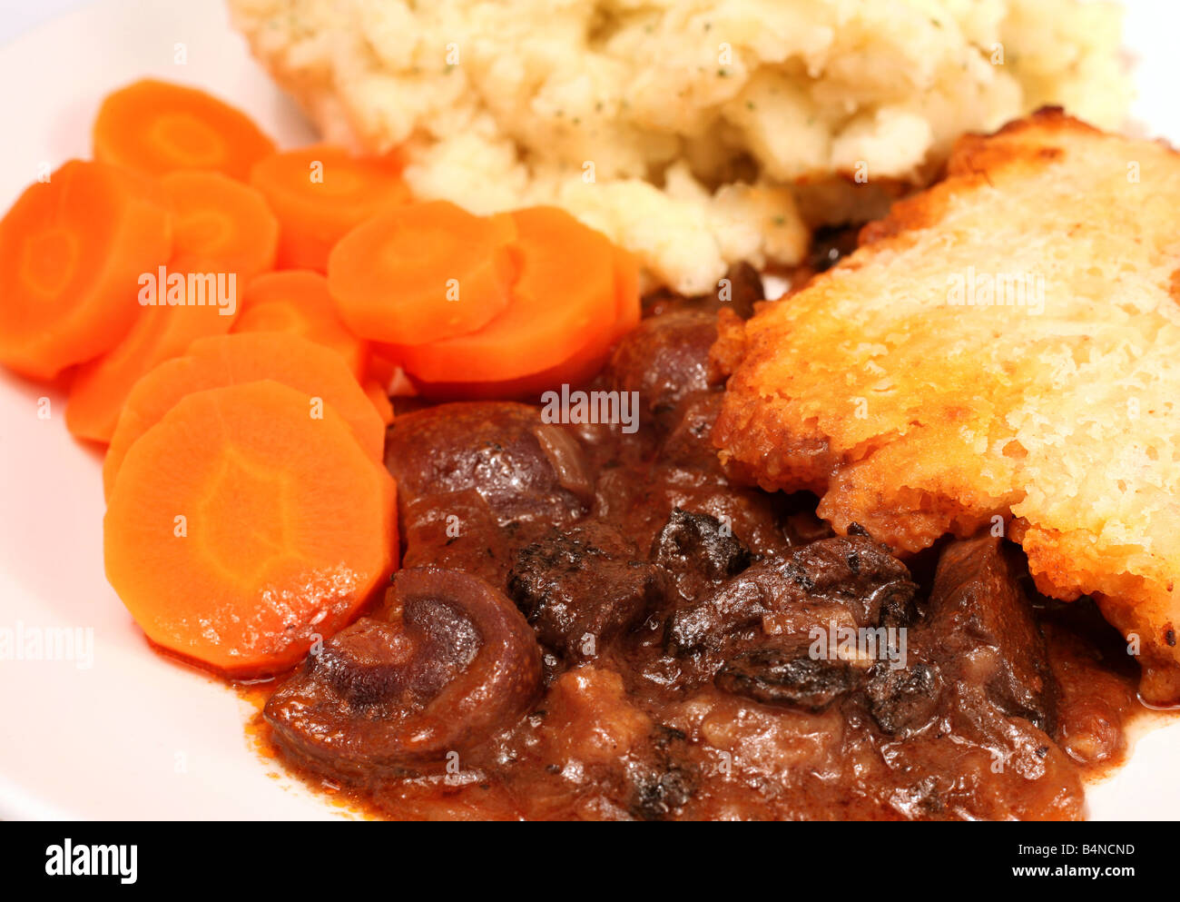 Side view of a meal of kidney and mushroom suet crust pie served with