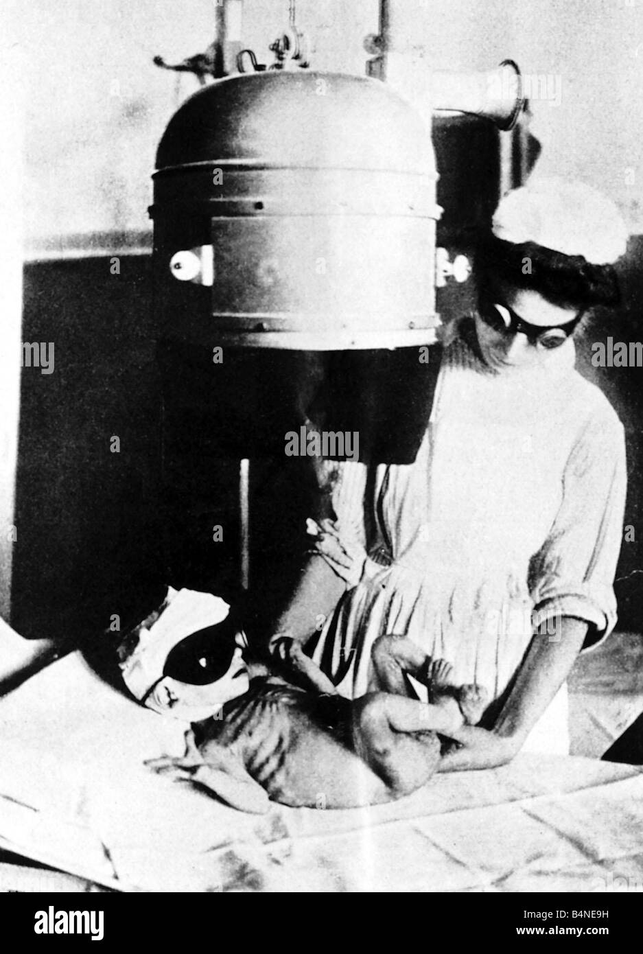 World War One A nurse working for the Save The Children Fund wearing protective goggles x rays an under nourished baby during the Great War Circa 1915 Stock Photo