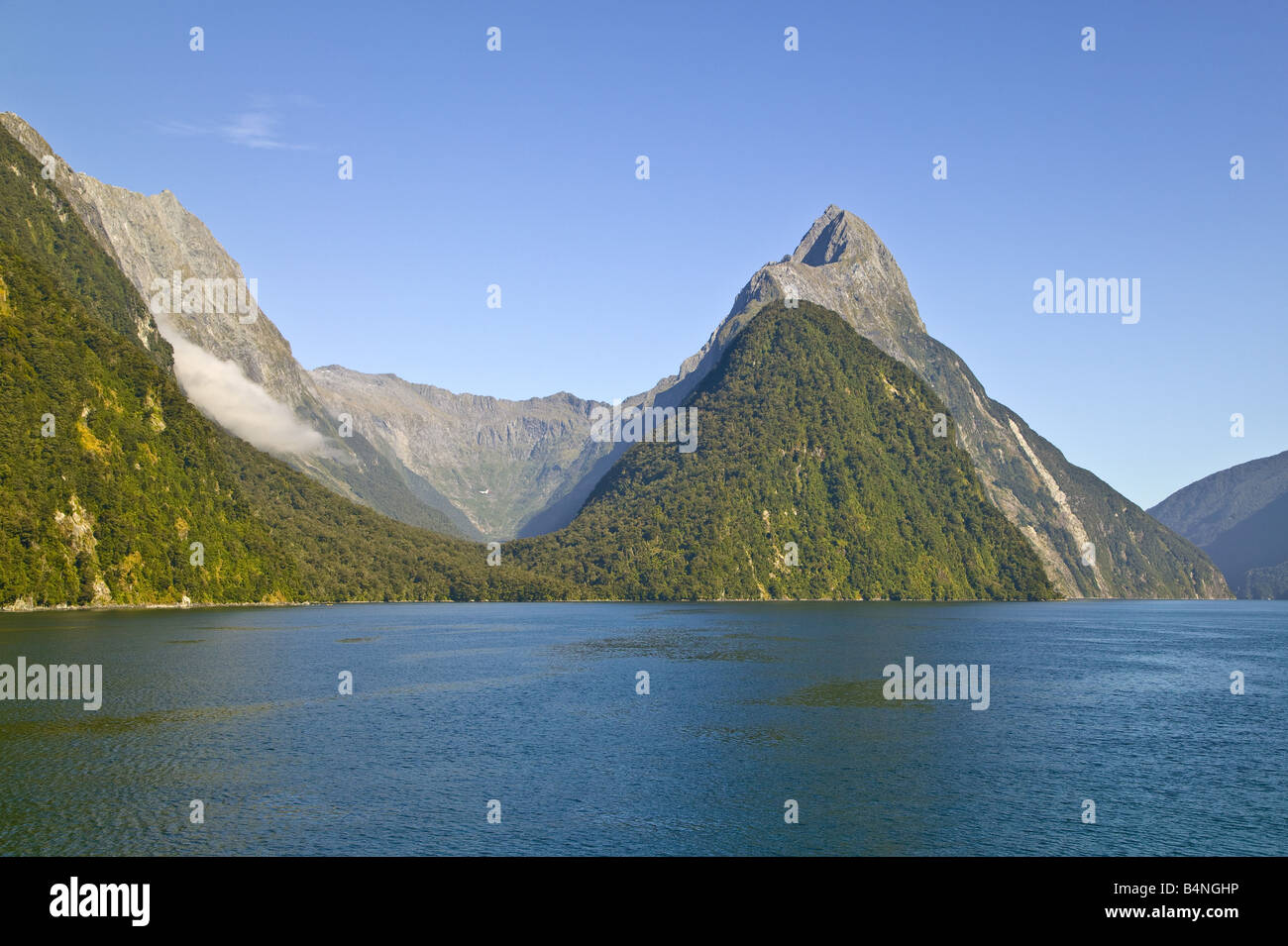 Mitre Peak, Milford Sound, South Island, New Zealand with inland valley showing under a blue sky. Stock Photo