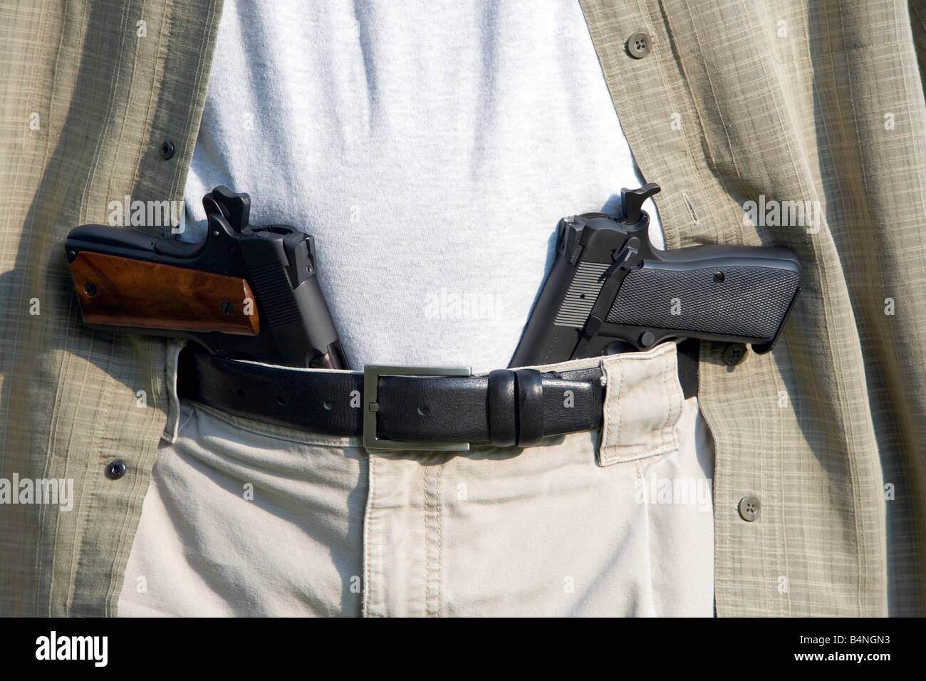 Two handguns sits in a man's belt. Stock Photo