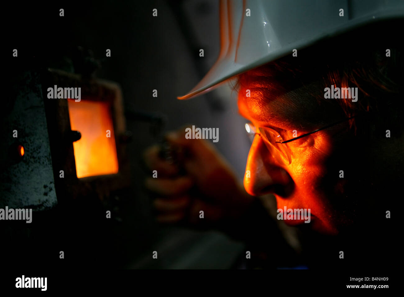 Furnace burning wood chippings to generate electricity Man inspecting