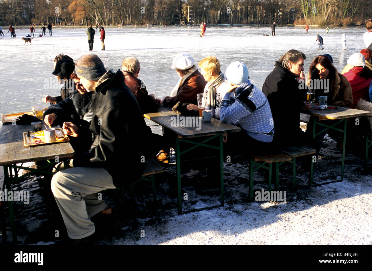 Customers in winter clothing enjoy an afternoon at the Seehaus Beer Garden in Munich's snow clad Englischer Garten Stock Photo