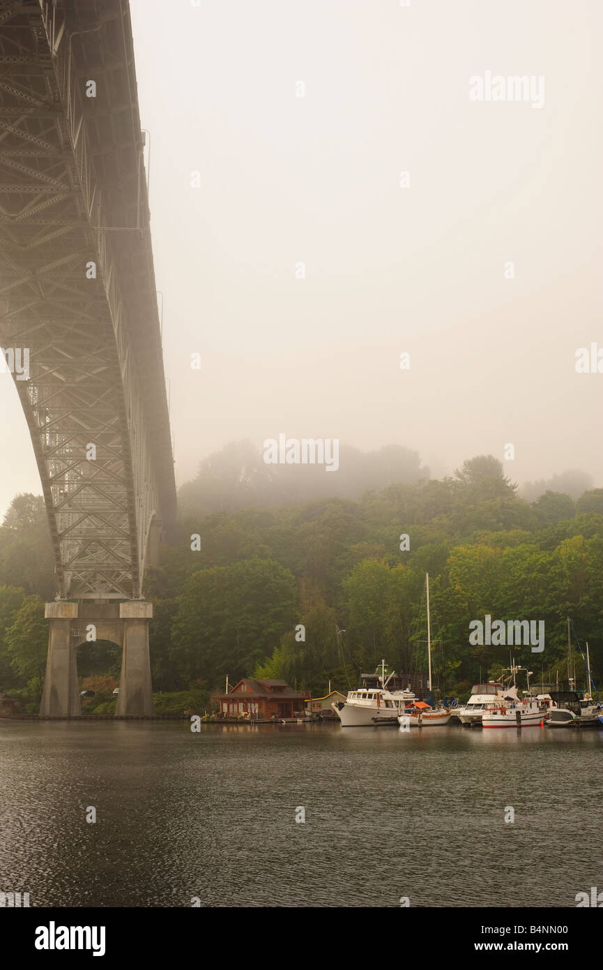 steel bridge and house boats below on misty morning Stock Photo