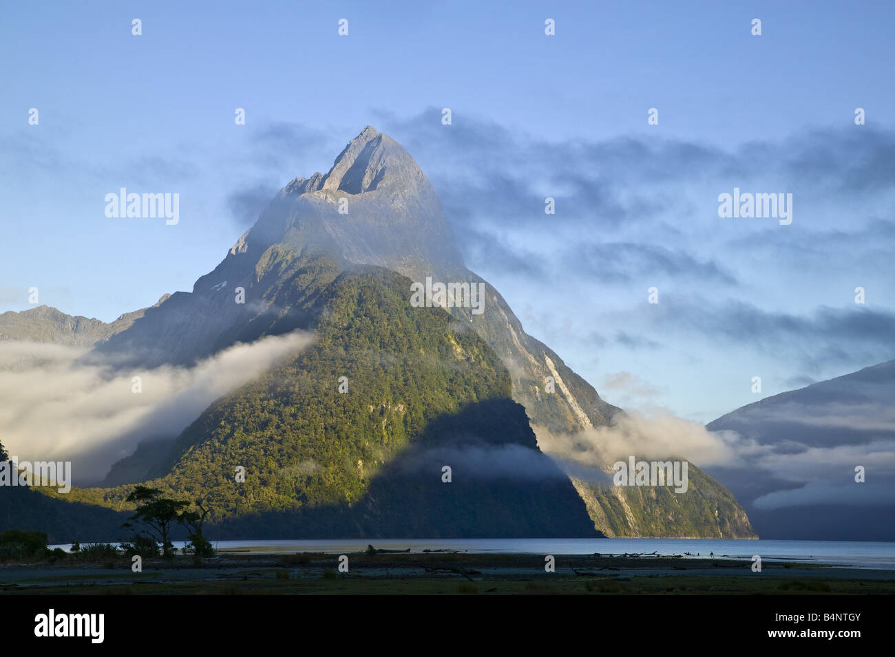 Mitre Peak in the early morning with clouds in the valley and across the peak Stock Photo