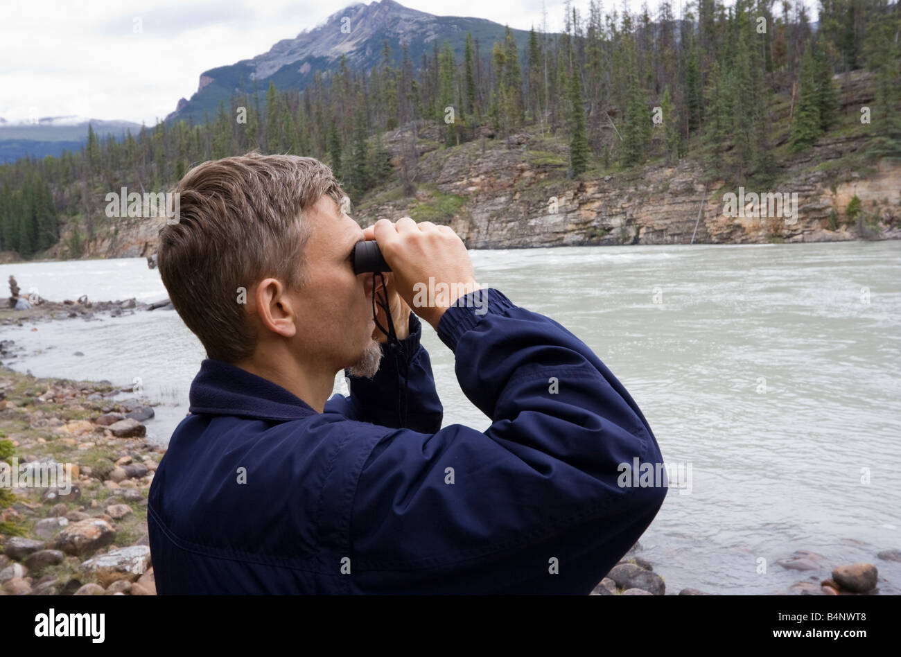 park ranger looking through binoculars athasbasca river jasper national park canada Stock Photo