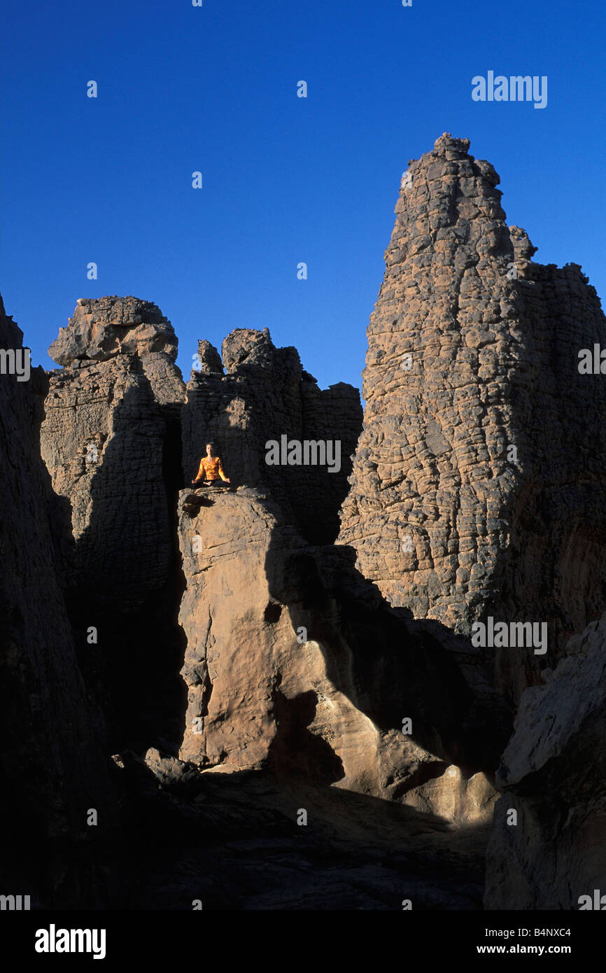 Algeria Djanet National Park Tassili n Ajjer UNESCO World Heritage site Tourist meditating Sahara desert Stock Photo