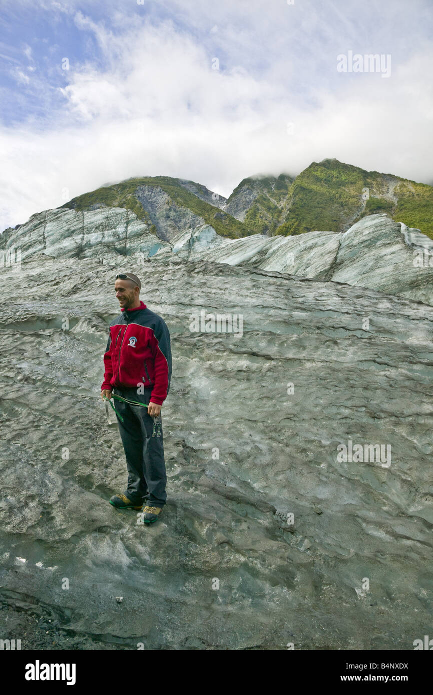 Tour guide holding crampons on the ice of Fox Glacier, South Island, New Zealand Stock Photo