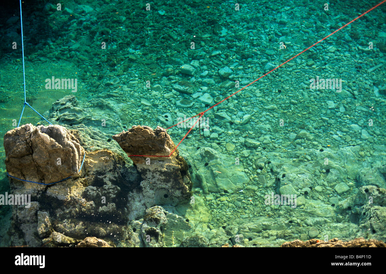 Blue and red yacht mooring ropes attached to rocks in the harbour at