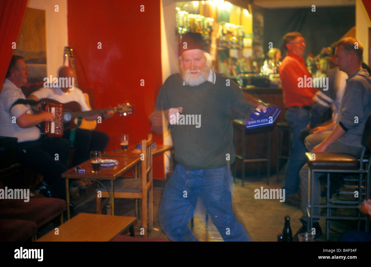 an elderly man with an ashtray in his hand dancing to pub music in Donegal Town Stock Photo