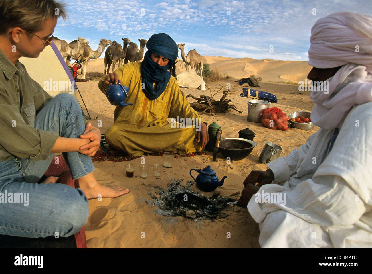 Algeria Tourist woman having tea with Tuareg people Sahara