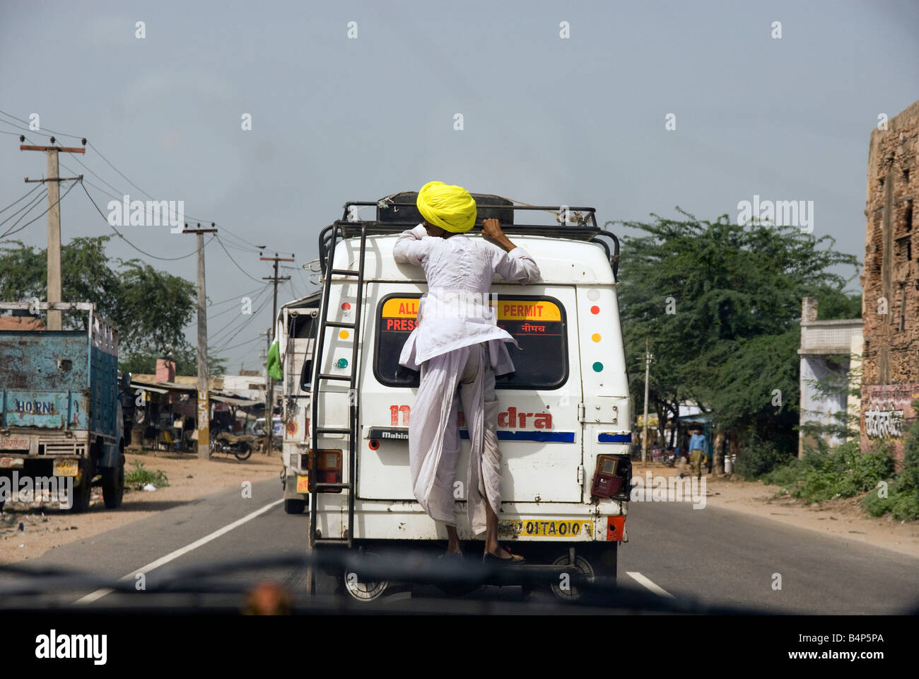 India Rajasthan Local man holding on to the back of a van Stock Photo