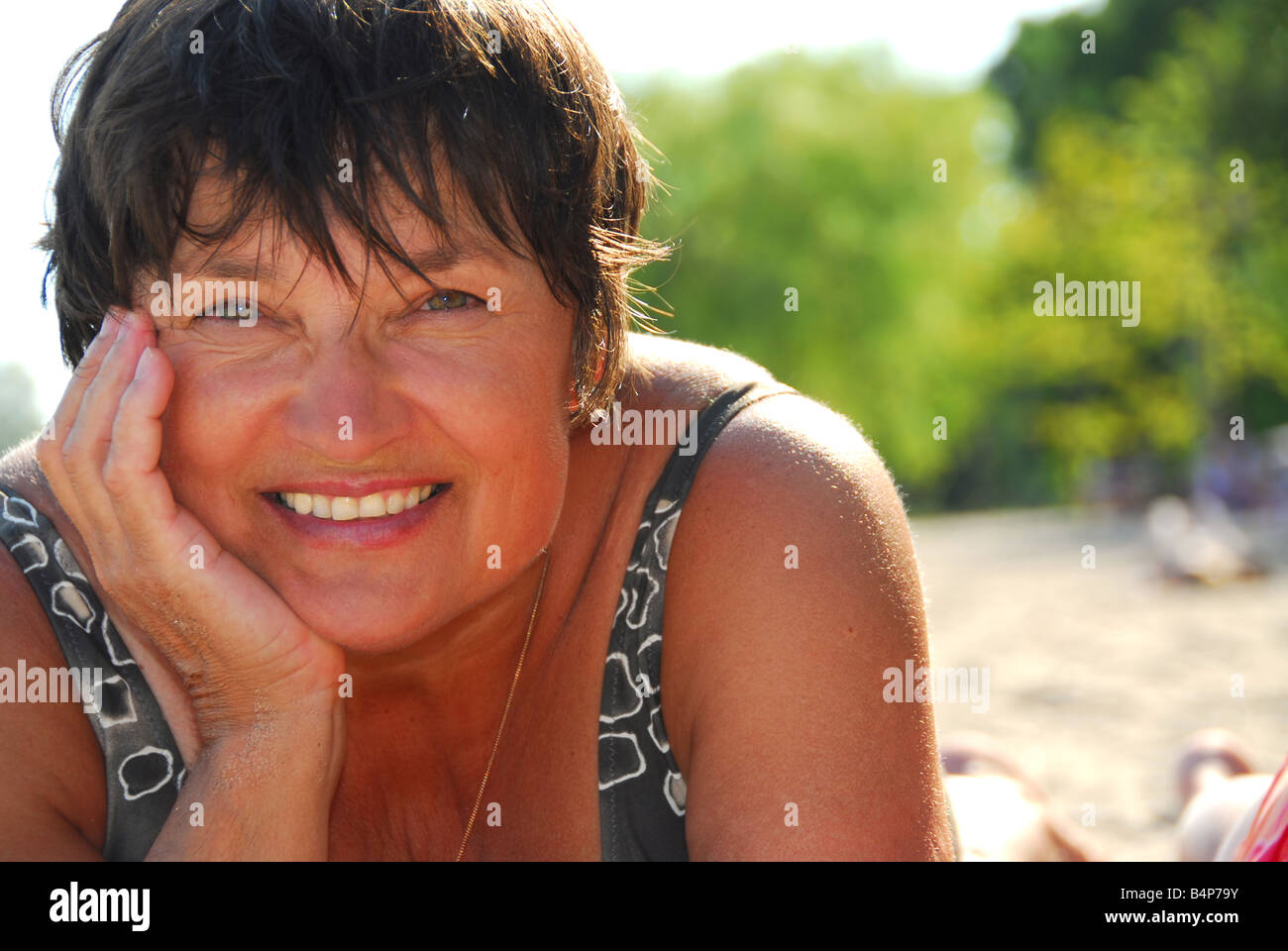 Portrait of a mature woman lying on a sandy beach Stock Photo - Alamy