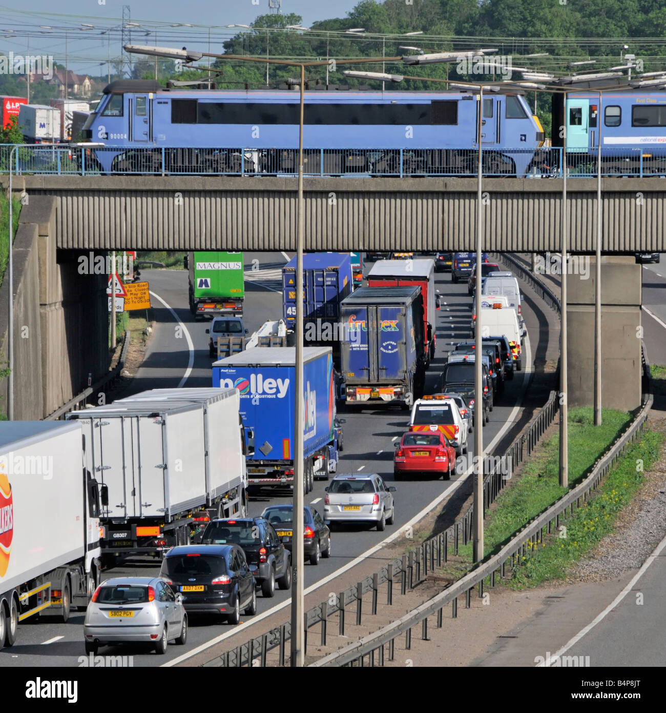 Transport choice M25 motorway nose to tail slow moving traffic watching fast passenger train on railway bridge junction 28 Brentwood Essex England UK Stock Photo