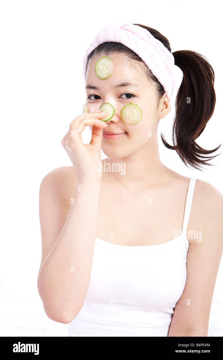 Young woman applying cucumber on face, portrait Stock Photo