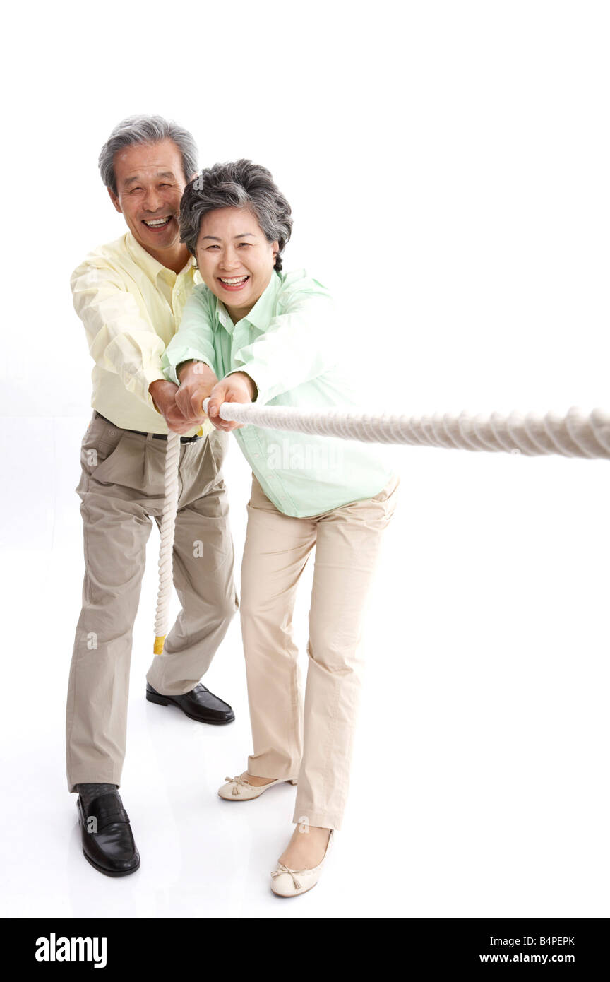 Mature couple playing tug of war , smiling, portrait Stock Photo