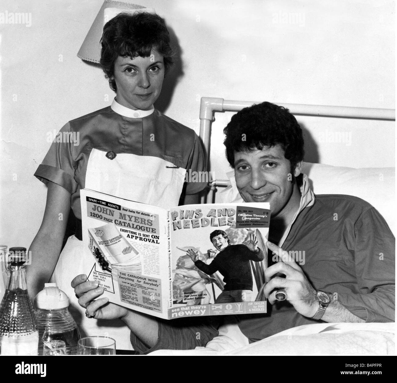 Tom Jones has his tonsils out The 25 year old singer had the operation Wednesday at the London Clinic and expects to be out of action for the next three weeks The Singer is photographed in the clinic after his operation looking at a woman s magazine Pins and Needles with a picture of himself on the cover Also in the picture is Sister Margaret Wilkinson of Barmouth North Wales May 1965 Stock Photo
