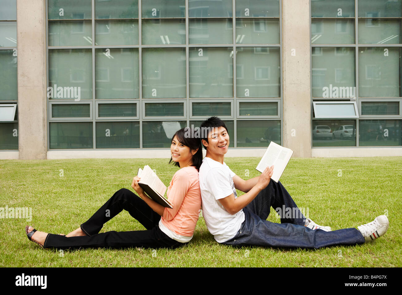 Young man and woman sitting back to back Stock Photo Alamy