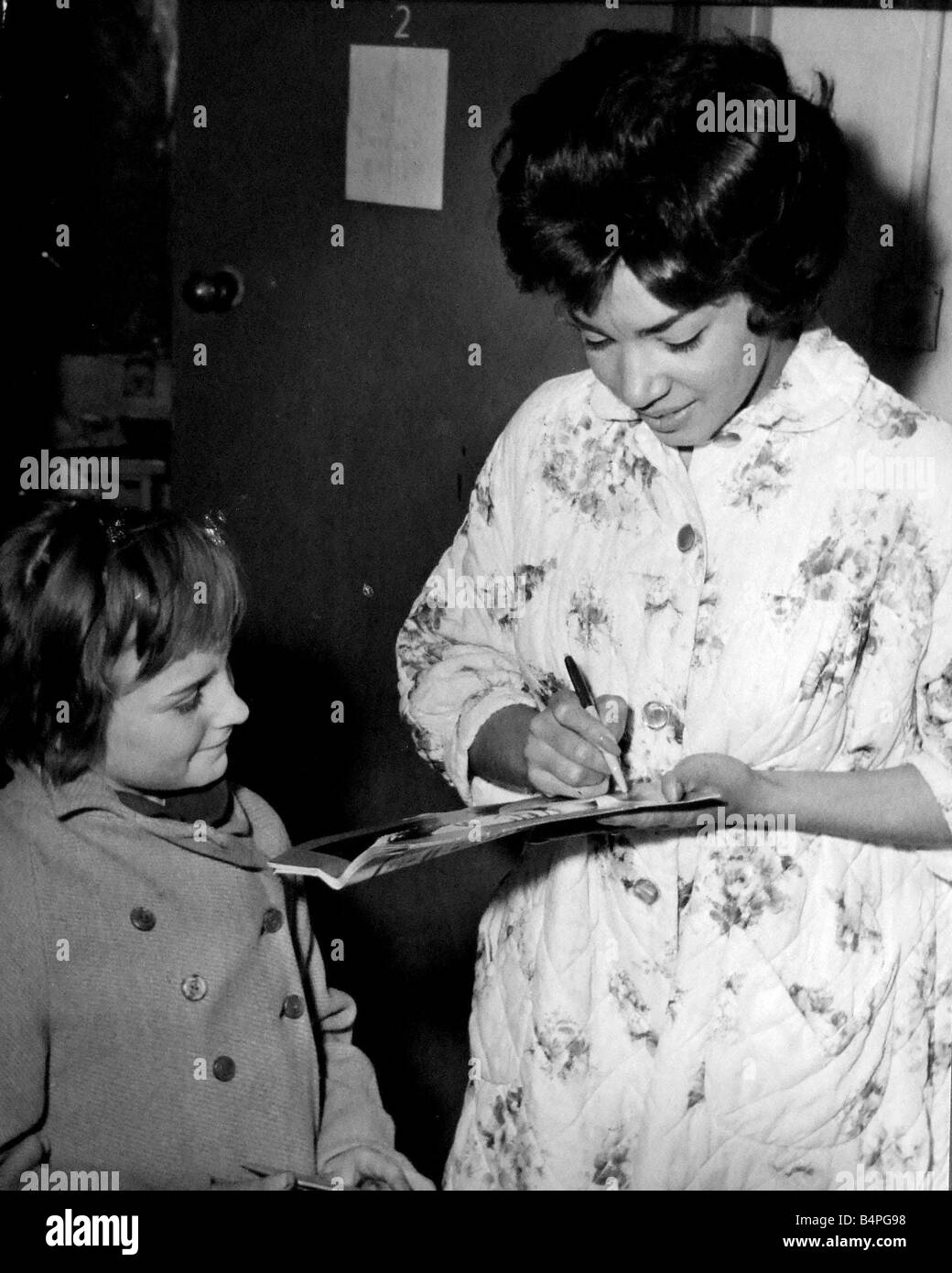 Shirley Bassey the Cardiff born singer returned home to Cardiff for a one night show at the Sophia Gardens Pavilion Picture shows one lucky autograph hunter Linda Davies of Bala Road Gabalfa watching Shirley in her dressing gown sign her programme 27th Nov 1961 Stock Photo