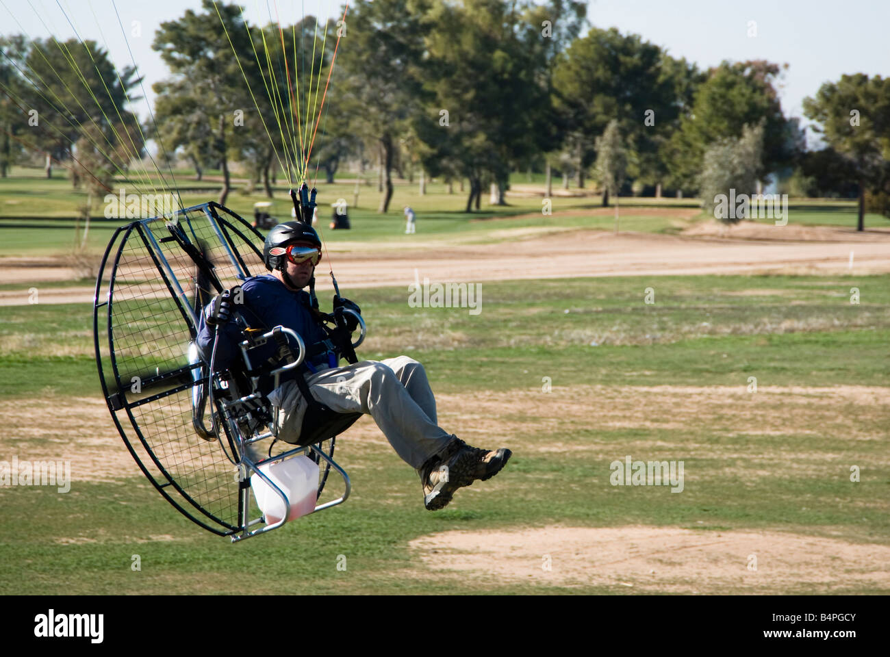 a powered paraglider pilot makes a low pass over the landing area Stock Photo