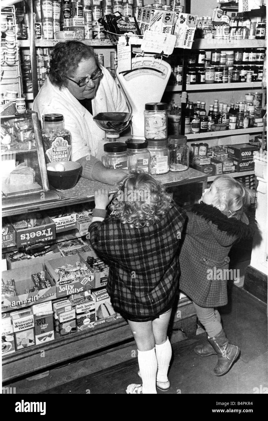 A shopkeeper serves children sweets at their local corner shop in