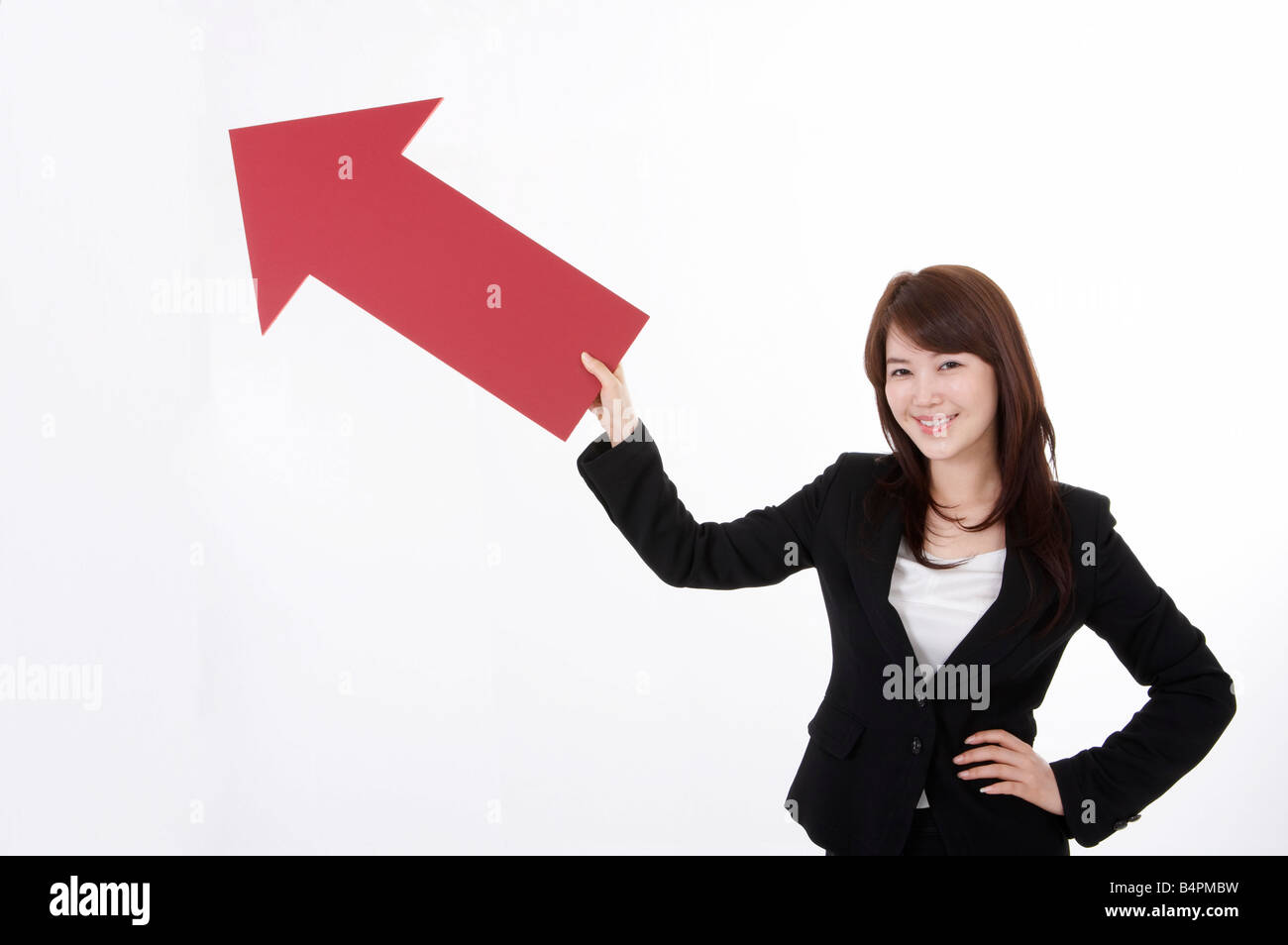 Cheerful businesswoman holding red arrow sign Stock Photo - Alamy