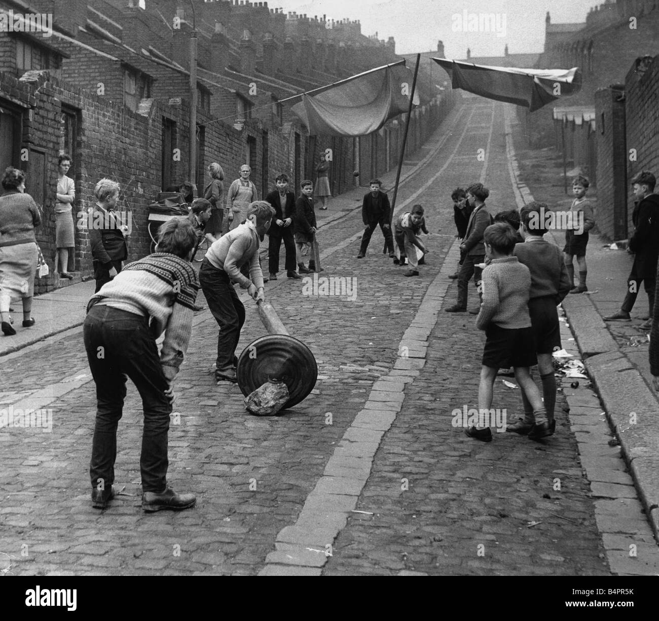Children kids playing cricket in the back lane street in Newcastle 1962 Children playing in the slums Stock Photo