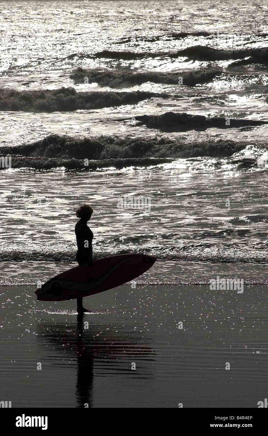Surfer with board in hand looks out to sea at Rest Bay Porthcawl which has been awarded the prestigous Blue flag 7th March 2002 Stock Photo
