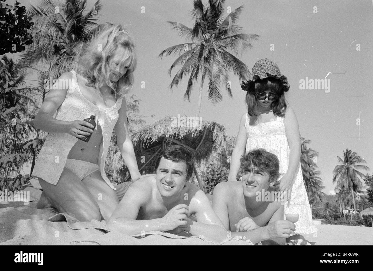 Comedian actor and publisher Peter Cook with his wife Wendy right with Dudley Moore and Suzy Kendall seen here having suntan oil rubbed into their backs during a holiday in Grenada March 1966 Stock Photo