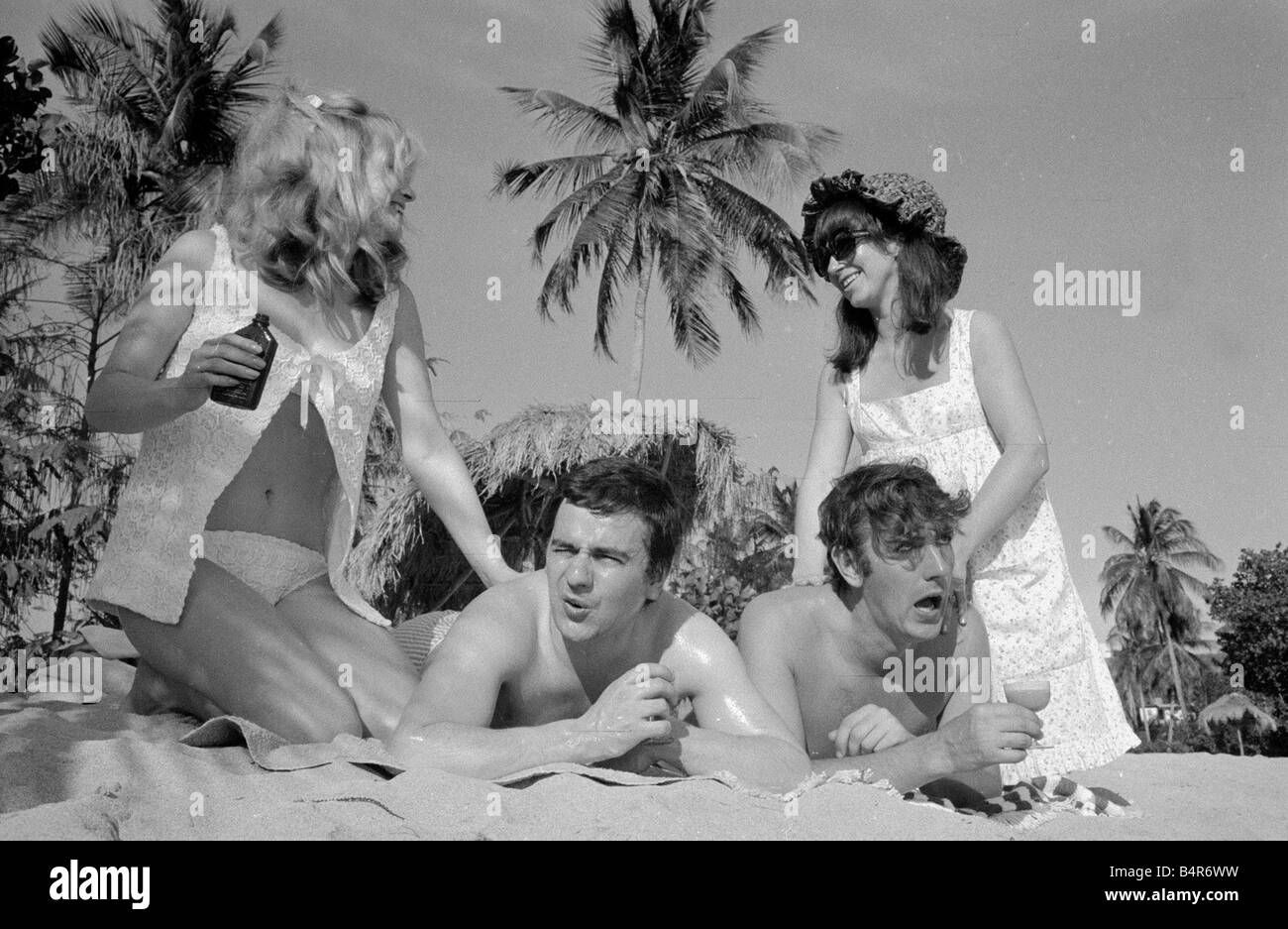 Comedian actor and publisher Peter Cook with his wife Wendy right with Dudley Moore and Suzy Kendall seen here having suntan oil rubbed into their backs during a holiday in Grenada March 1966 Stock Photo