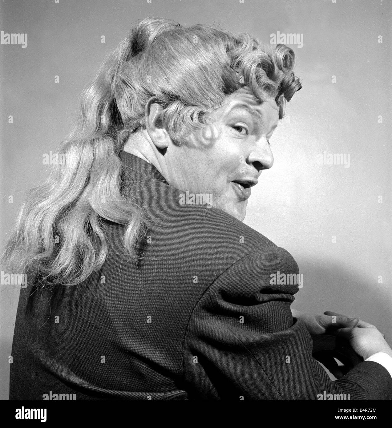 Comedian Benny Hill pictured at home wearing a wig May 1958 Stock Photo