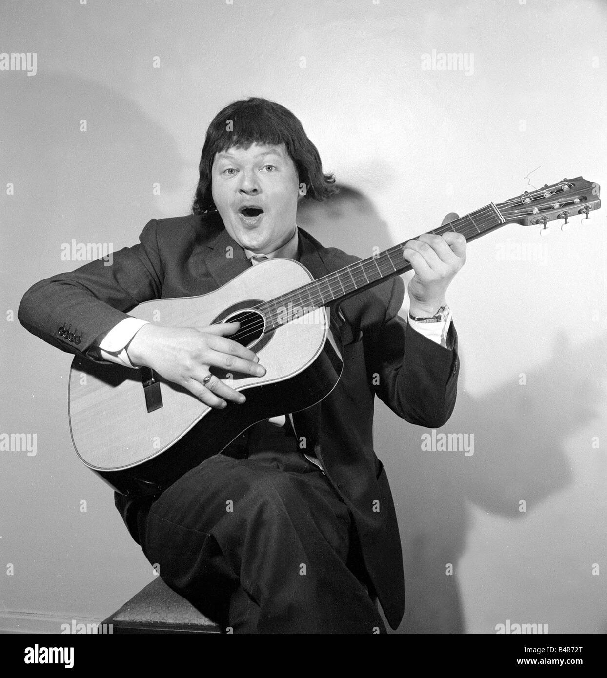 Comedian Benny Hill pictured at home wearing a wig and playing the guitar May 1958 Stock Photo