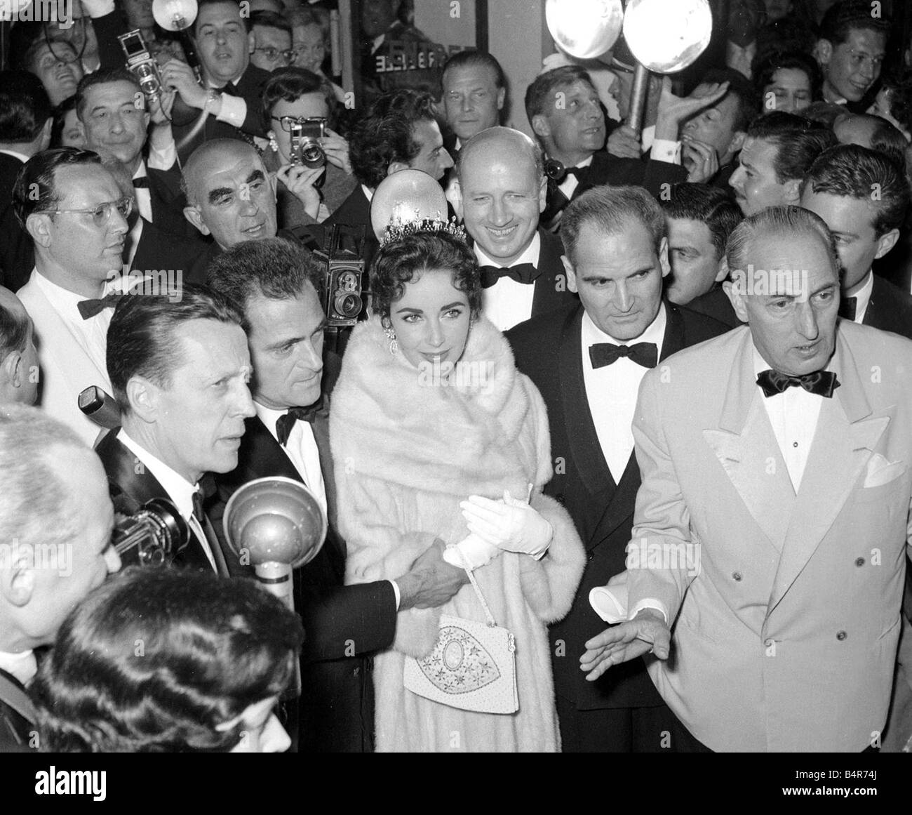 Elizabeth Taylor and husband Mike Todd surrounded by photographers in the theatre before showing of his film Round the World in Stock Photo