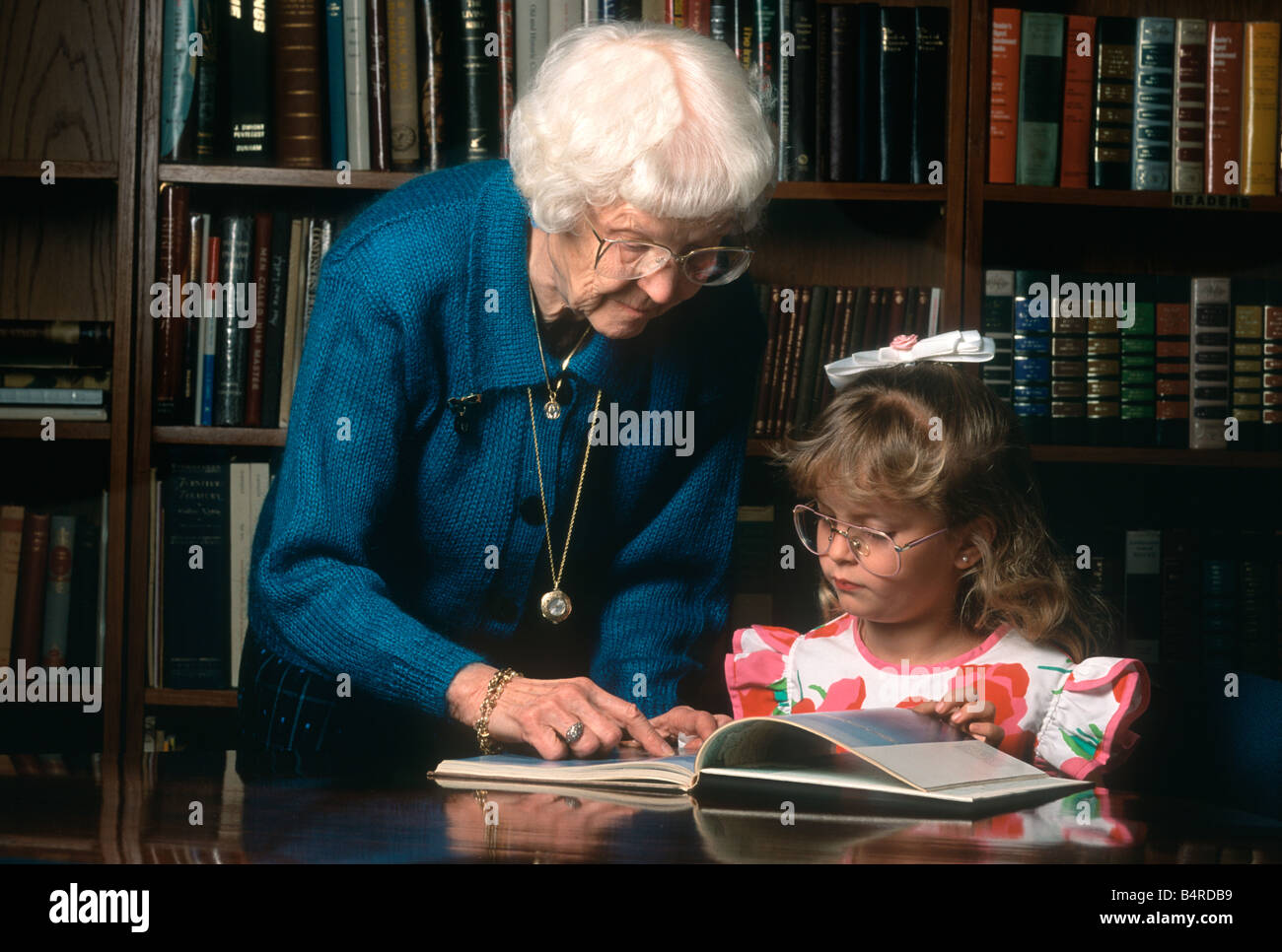Grandmother helping granddaughter in library Stock Photo