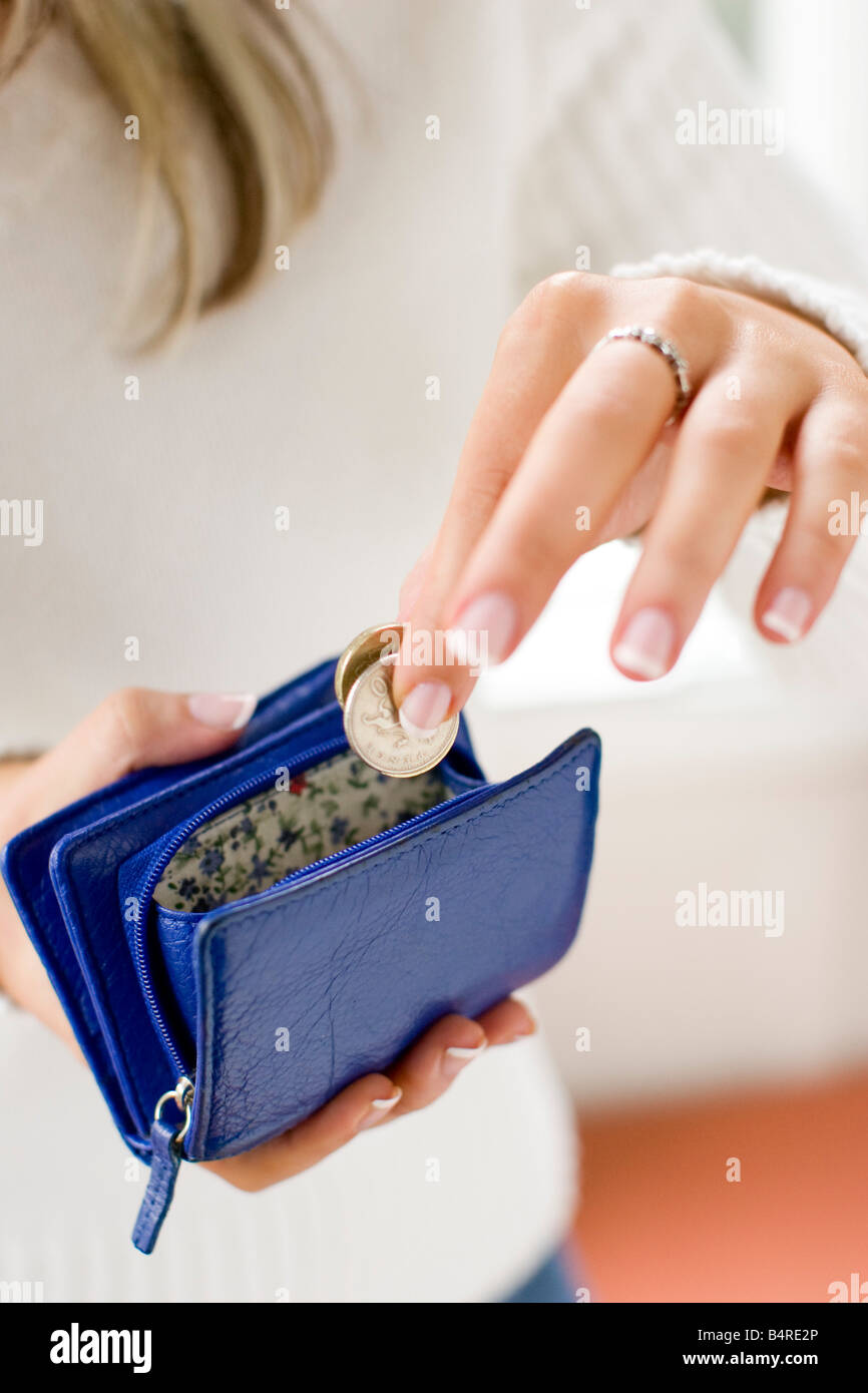 young woman putting coins in purse Stock Photo