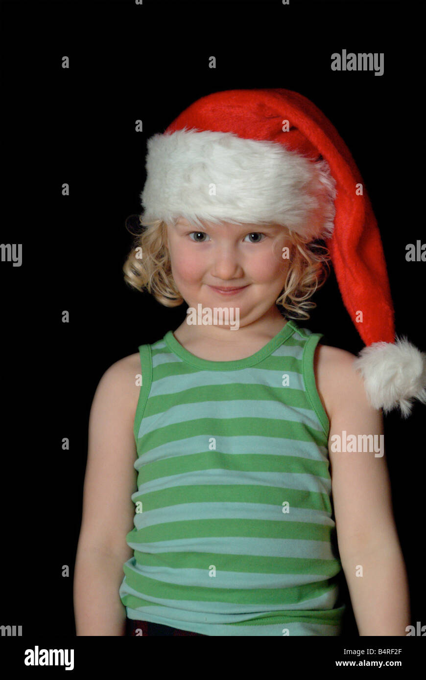 White girl wearing a red christmas hat and green stripy vest, smiling at camera Stock Photo